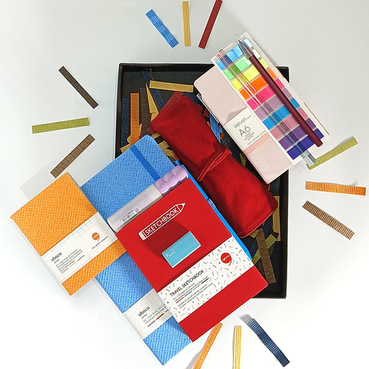 Collection of art supplies including notebooks, pencils, and color swatches on a white background