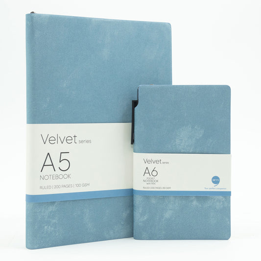A set of two sky blue velvet notebooks, one A5 size and one A6 size, with a blue ballpoint pen and labeled 'Velvet Series A5' and 'Velvet Series A6' respectively.