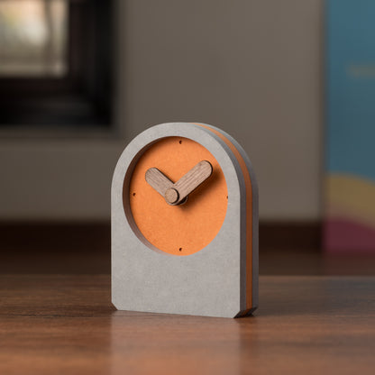 A square-shaped table clock with an orange front and gray back, featuring wooden hands and a digital display.